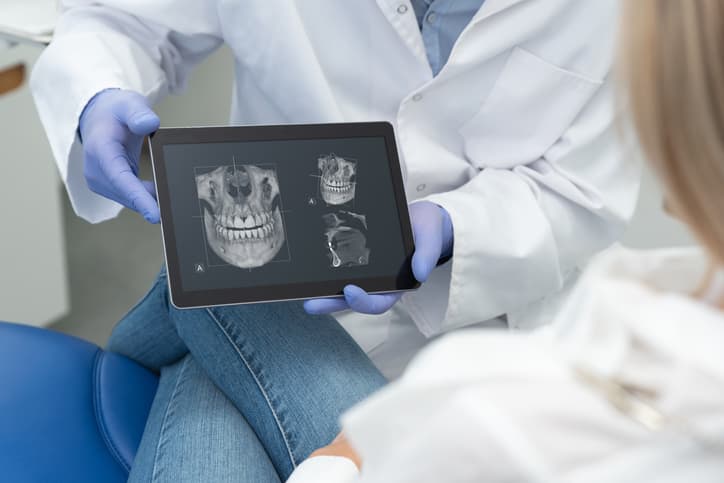 Zahnarzt zeigt der Patientin die Aufnahme des DVT-Röntgen